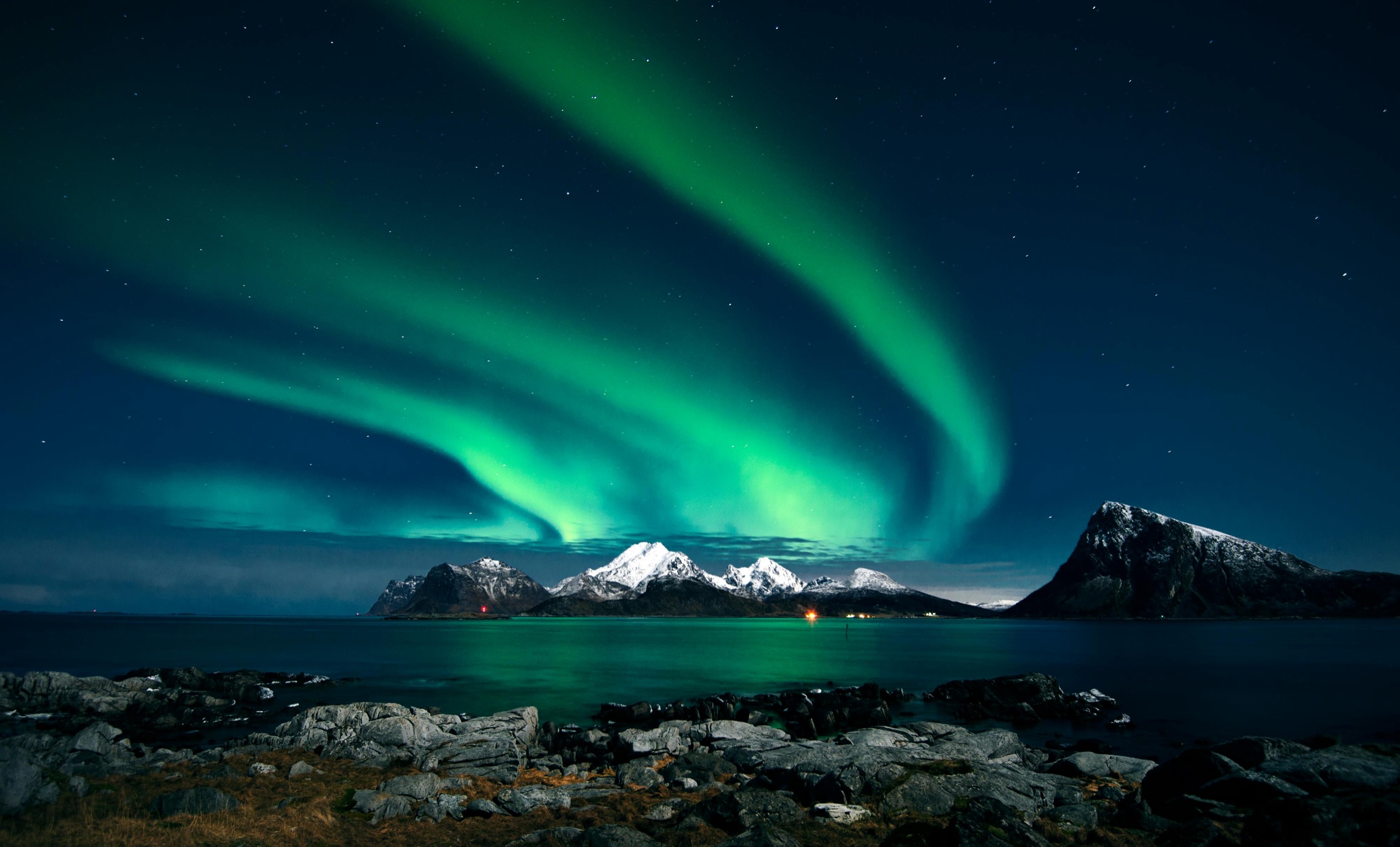 The aurora borealis in green ribbons above the snow-covered peaks of the Lofoten islands