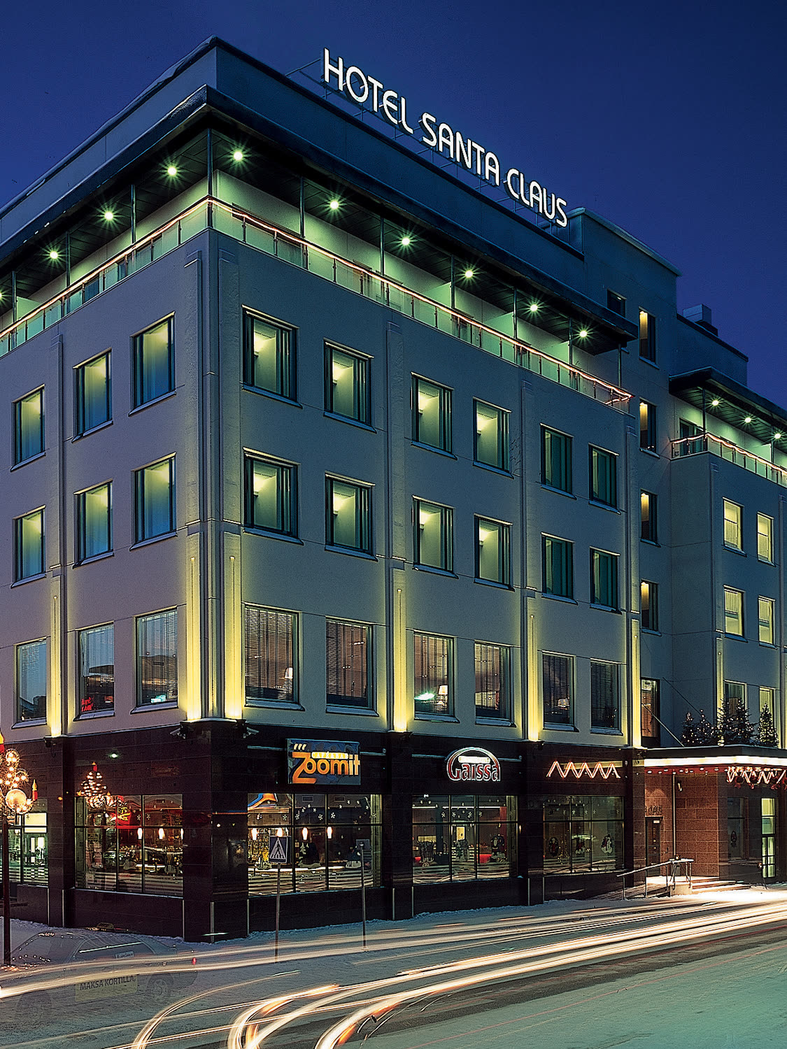 Hotel Santa Claus lit at blue hour on its corner in snowbound Rovaniemi
