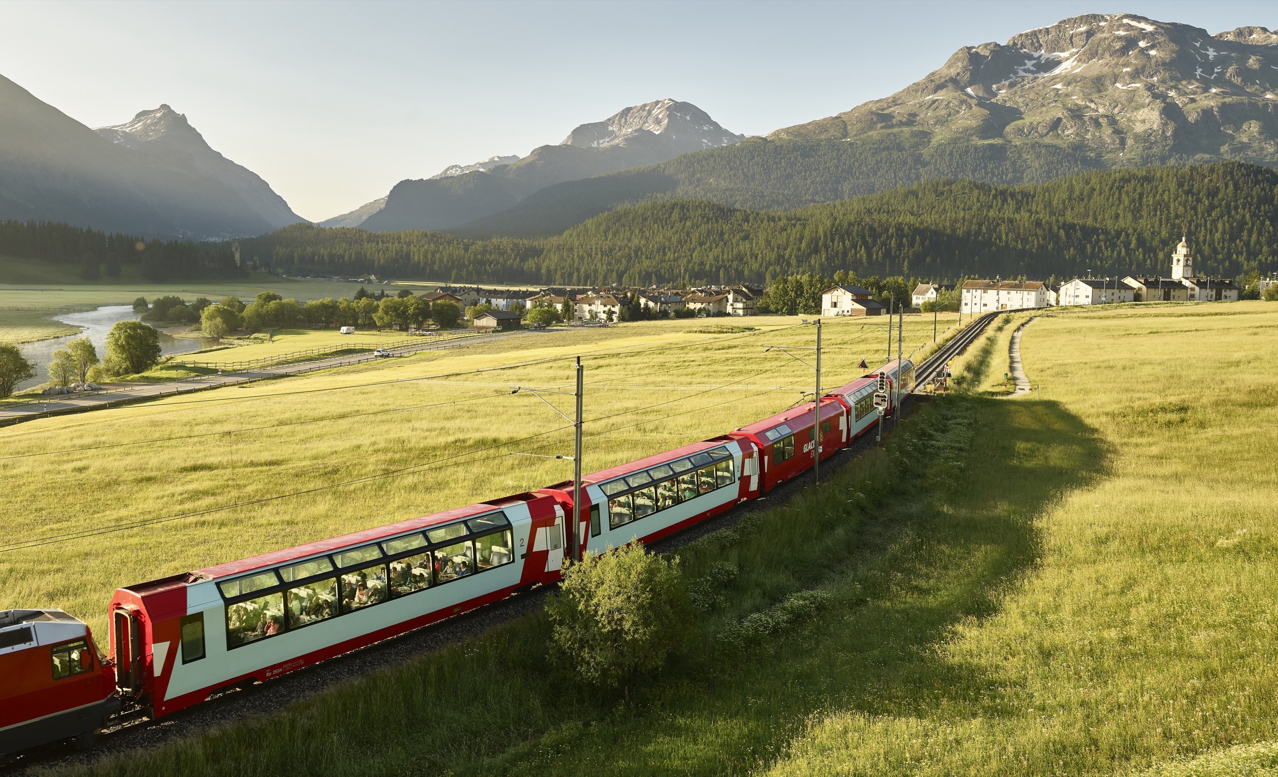 The Glacier Express through the Engadin meadows in evening light